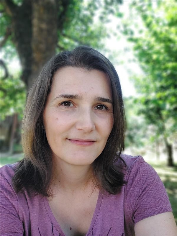 Liv Tymes, smiling, under the trees